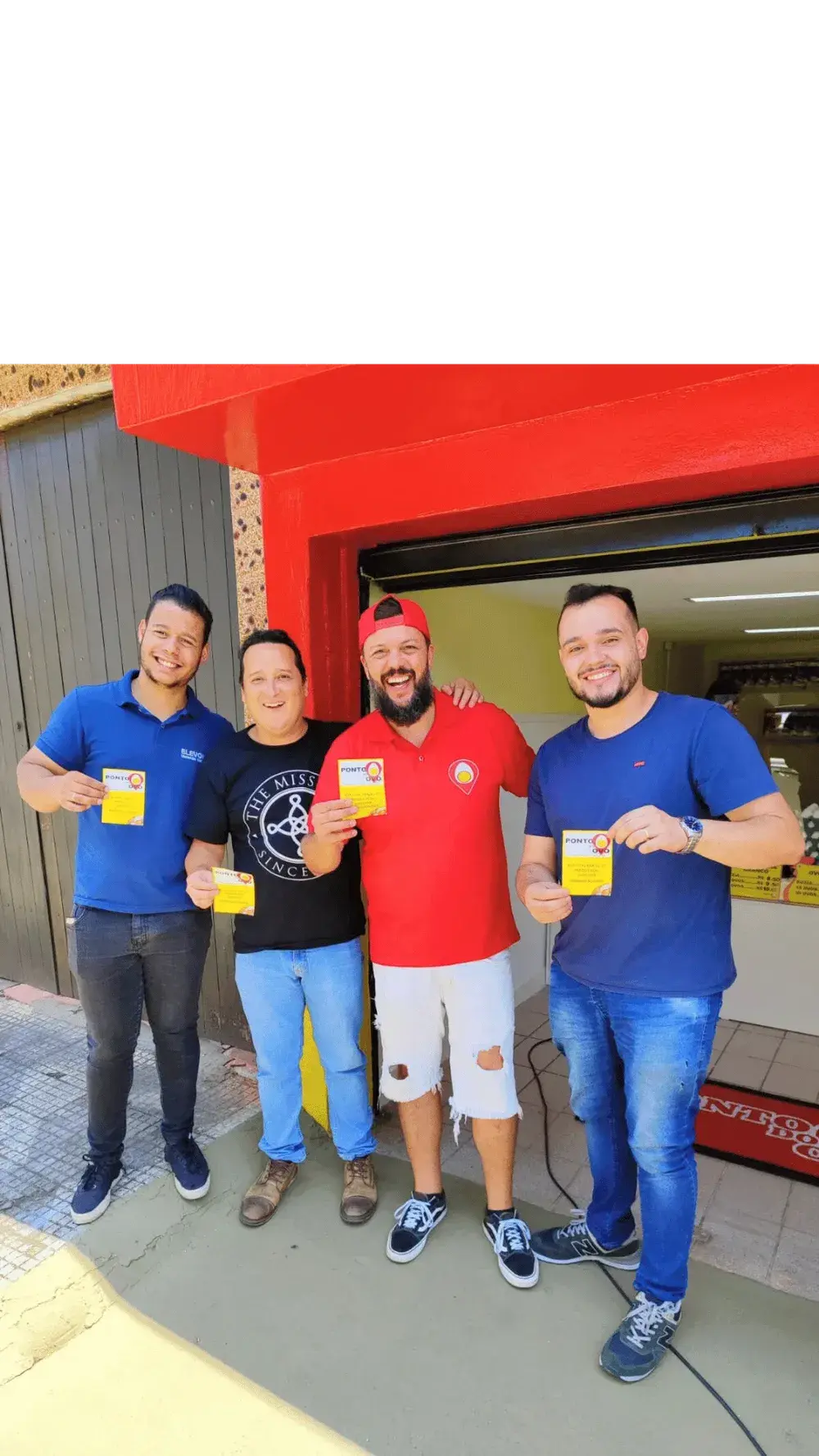 Equipe do Ponto do Ovo reunida em frente à loja, segurando cartões da marca